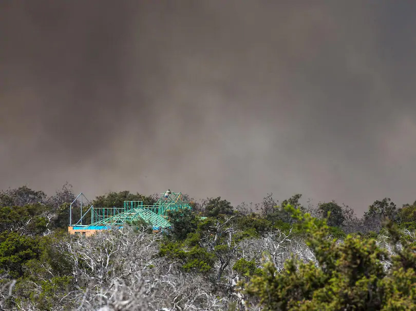 A man watches the bushfire from the roof of his partly completed home in Tranquil Drive, Esperance. Credit: The West Australian, Mogens Johansen, The West Australian